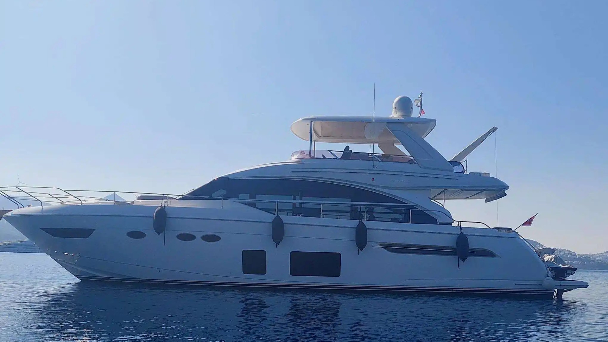 A luxury yacht on calm water under a clear blue sky.