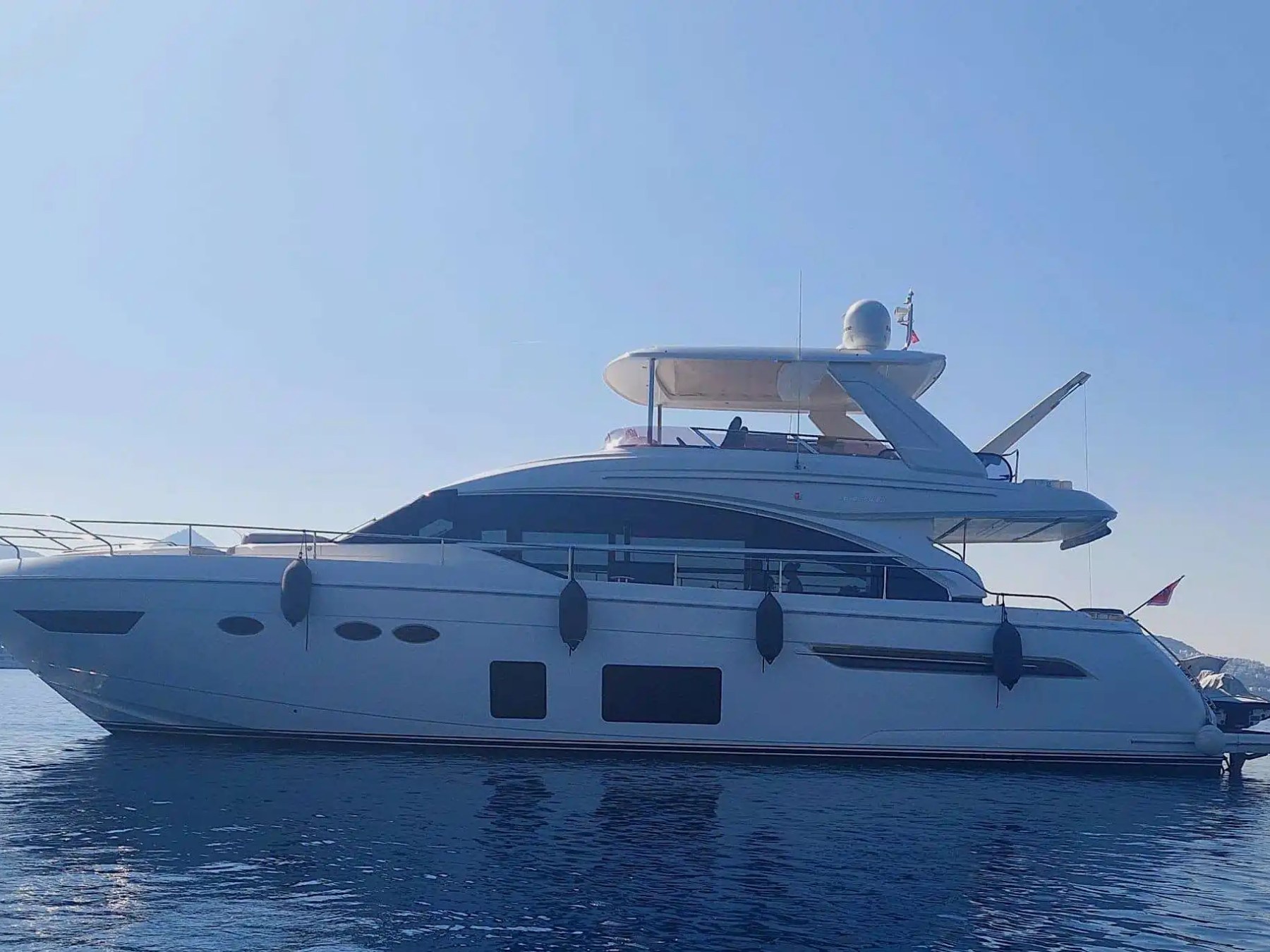 A luxury yacht on calm water under a clear blue sky.