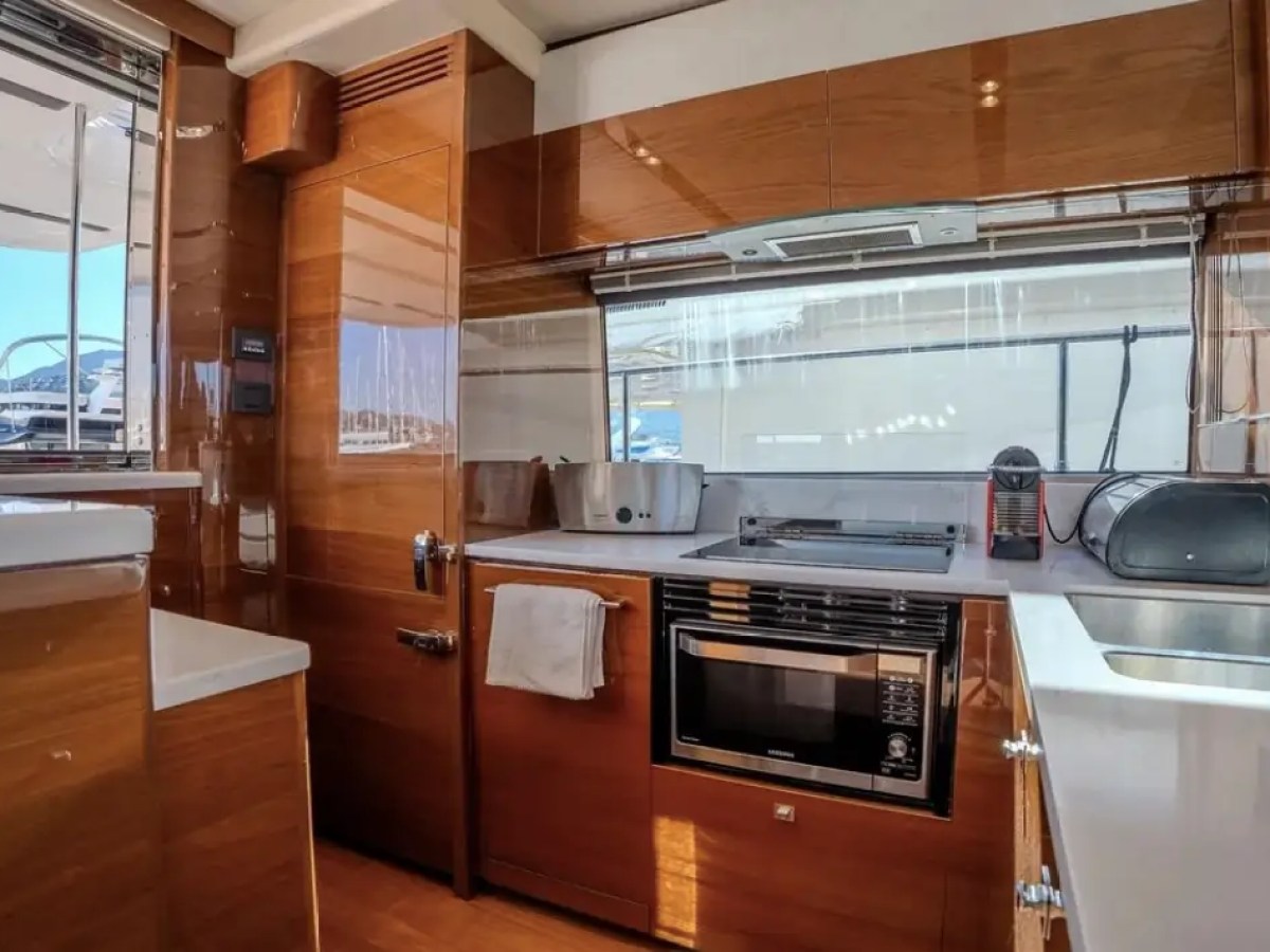 Modern yacht kitchen with wooden cabinets, sink, microwave, and appliances.