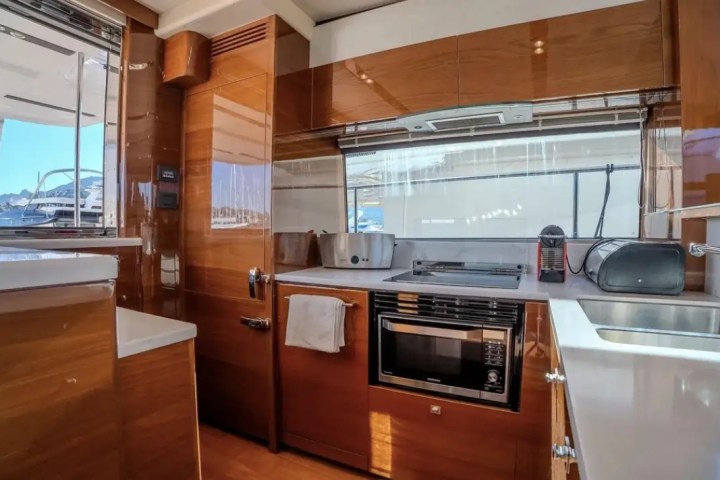Modern yacht kitchen with wooden cabinets, sink, microwave, and appliances.