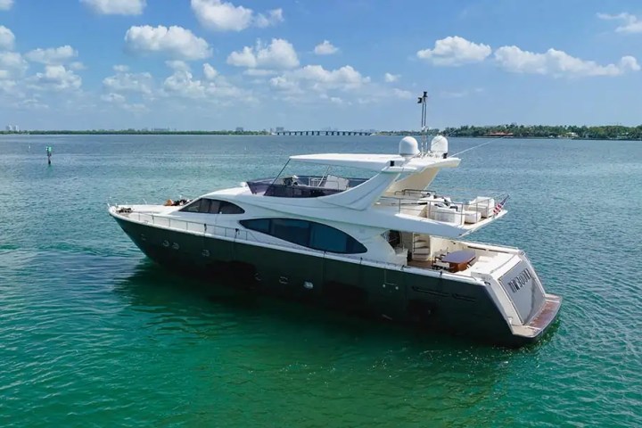 Luxury yacht floating on clear blue water under a partly cloudy sky.