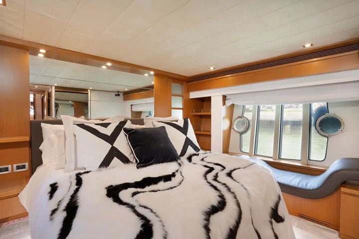 Luxurious bedroom on a boat with large windows, patterned bedding, and modern decor.