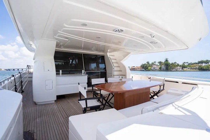 Luxury yacht deck with a dining table, chairs, and a sea view.