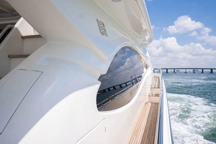 View from yacht deck showing sea, sky, and distant bridge in sunshine.