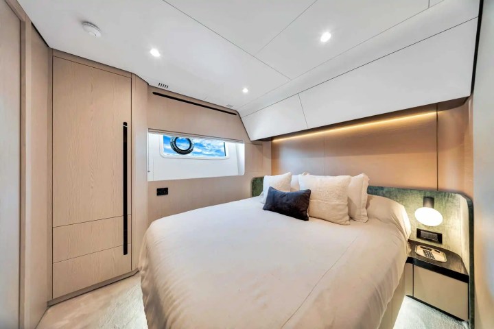Modern yacht bedroom with double bed, porthole window, and minimalist decor.