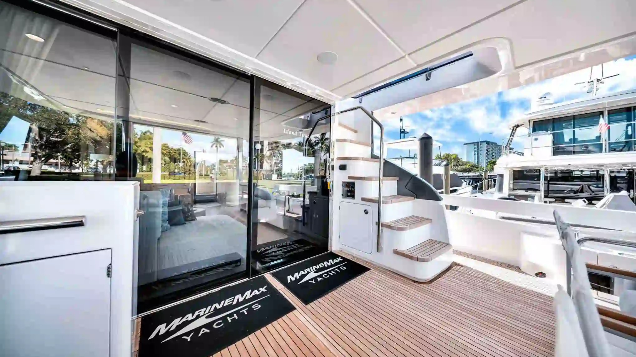 Luxury yacht deck with stairs, sliding glass door, and scenic marina view.
