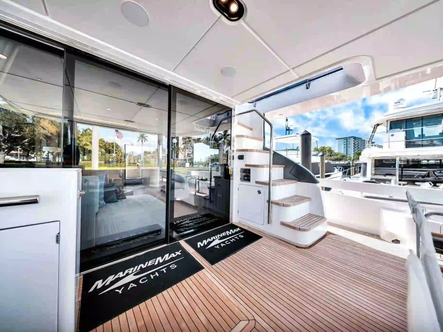 Luxury yacht deck with stairs, sliding glass door, and scenic marina view.