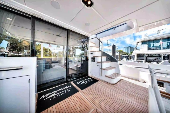 Luxury yacht deck with stairs, sliding glass door, and scenic marina view.