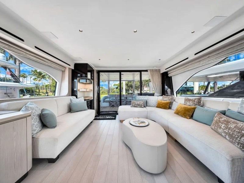 Spacious yacht interior with beige sofas, large windows, and decorative cushions.