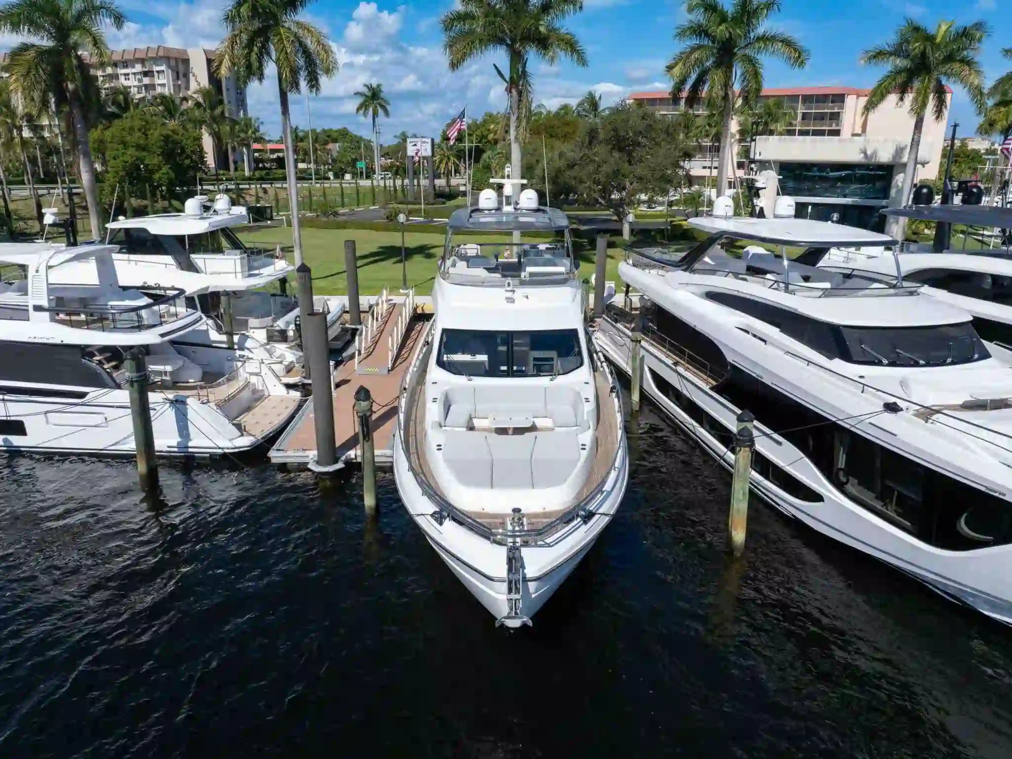 Four luxurious yachts docked at a marina with palm trees in the background.
