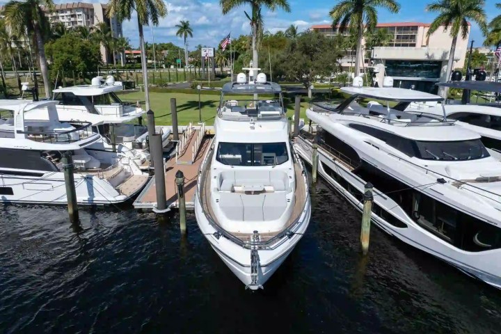 Four luxurious yachts docked at a marina with palm trees in the background.