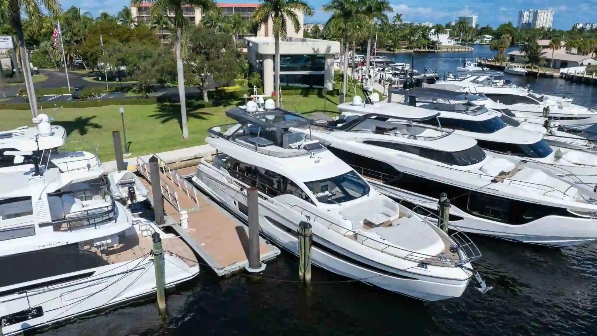Luxury yachts docked at a marina, surrounded by palm trees and green landscape.