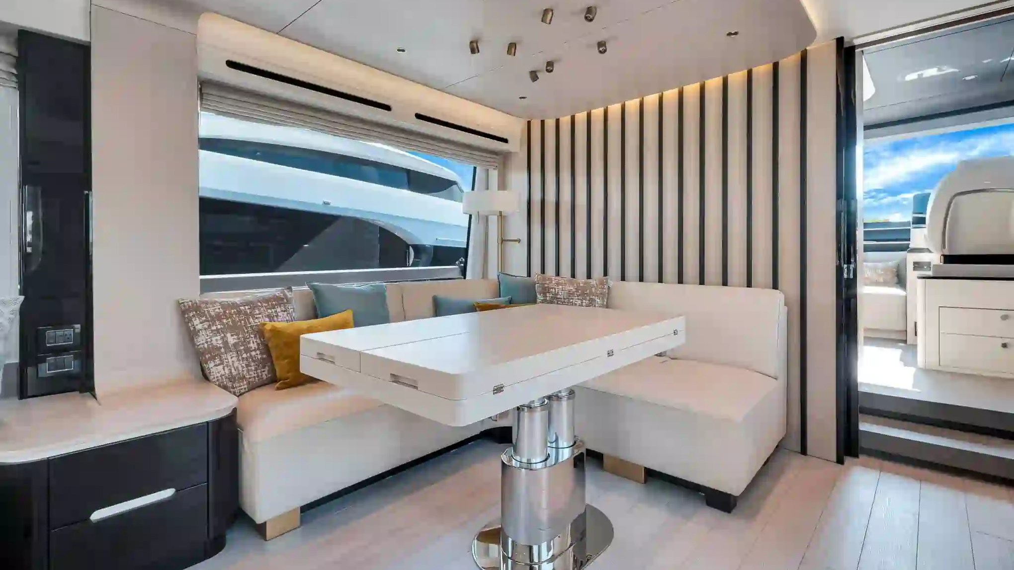 Modern yacht interior with a white sofa, adjustable table, and large window.