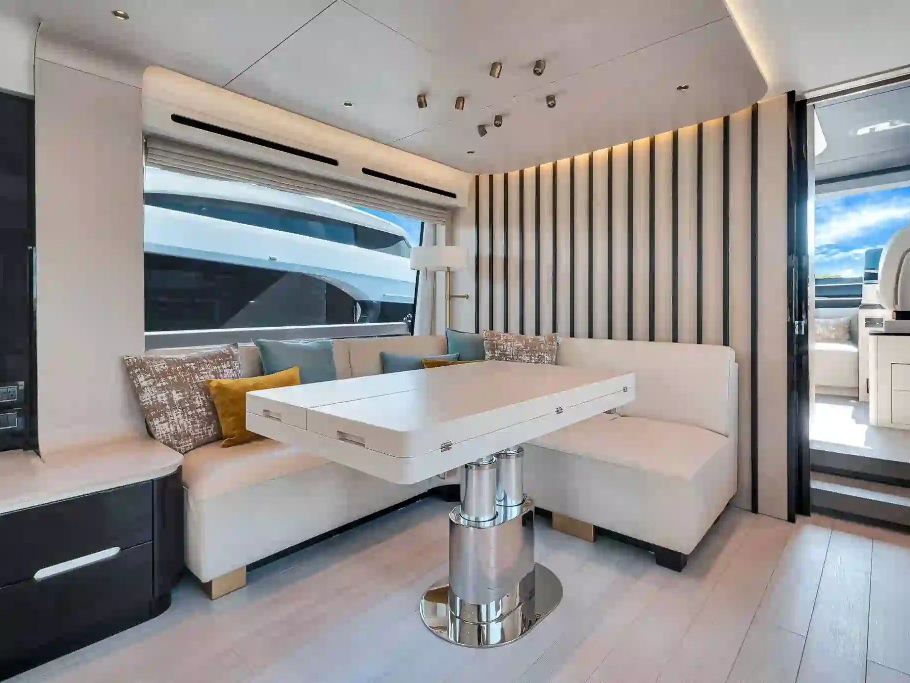 Modern yacht interior with a white sofa, adjustable table, and large window.