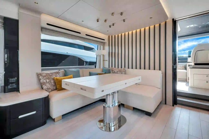 Modern yacht interior with a white sofa, adjustable table, and large window.