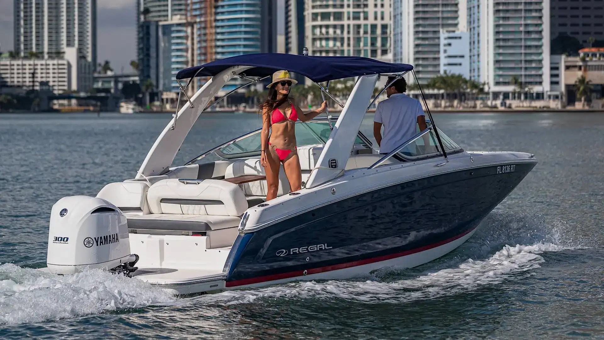 29' Regal Boat Rental cruising Biscayne Bay with guests aboard, blue hull, Yamaha outboard power, and Downtown Miami skyline views in South Florida.