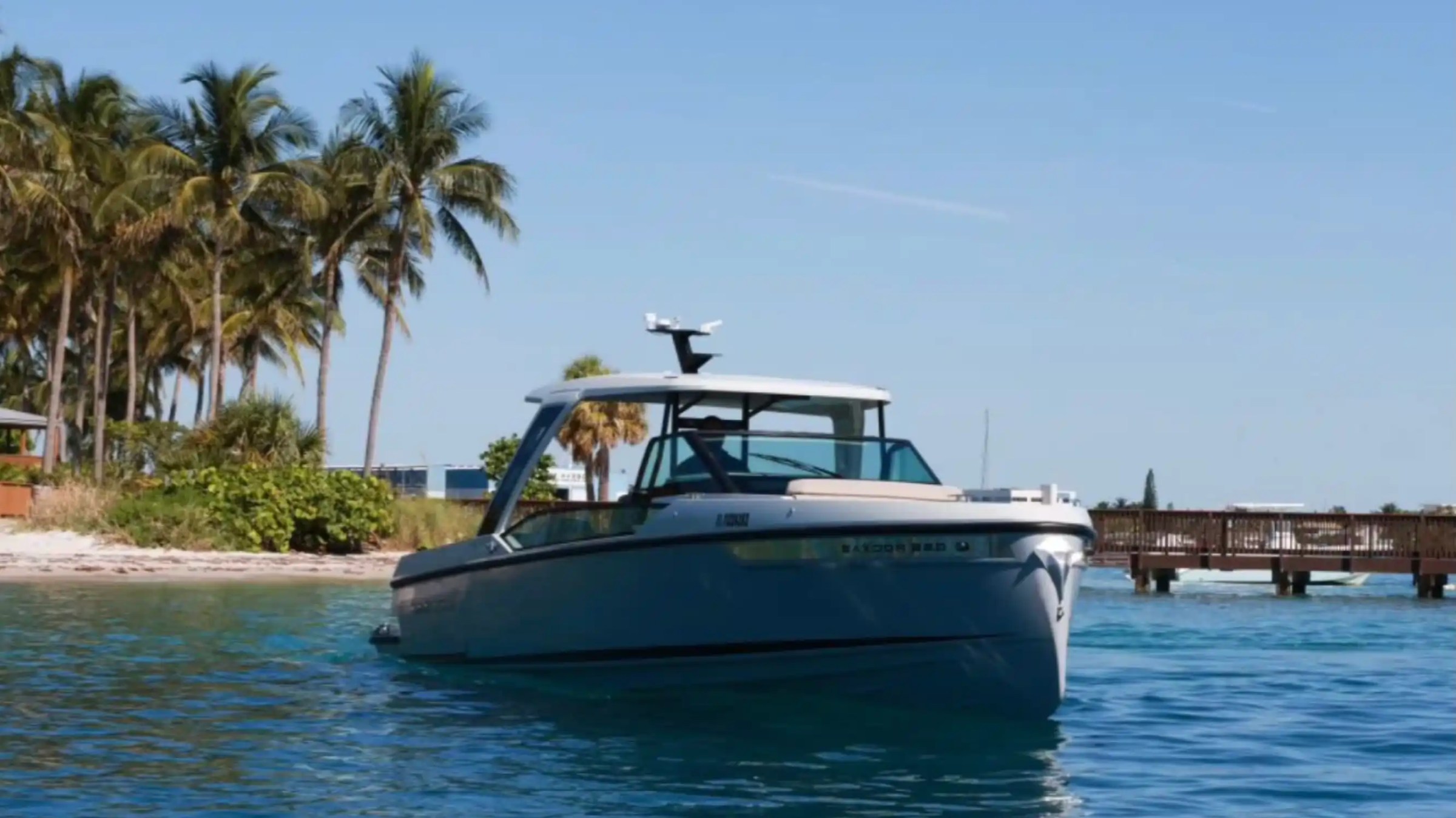 Boat near tropical island with palm trees and wooden dock.