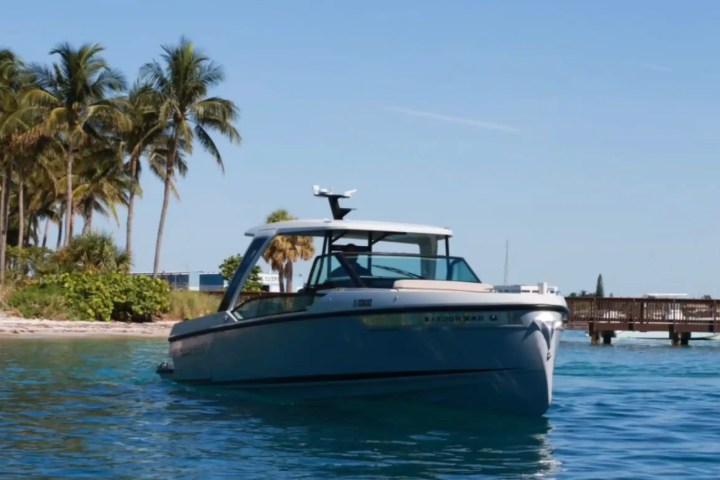 Boat near tropical island with palm trees and wooden dock.