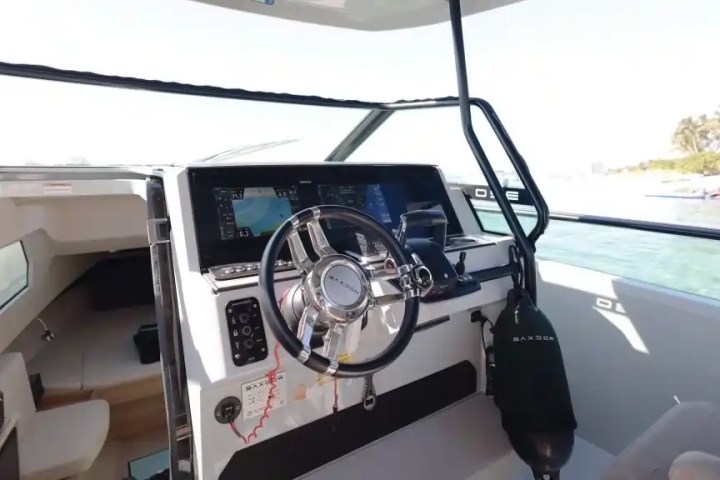 Boat cockpit with steering wheel, control panel, and cabin view.