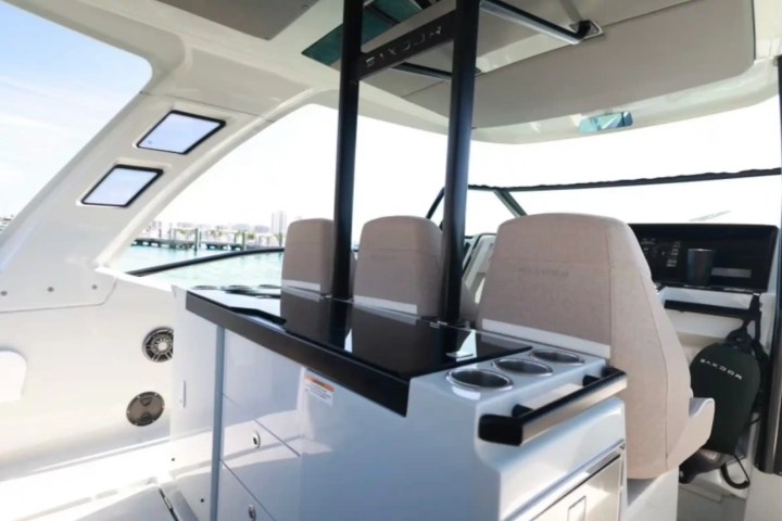 Interior of a modern boat with beige seats, black countertop, and windows showing a dock view.