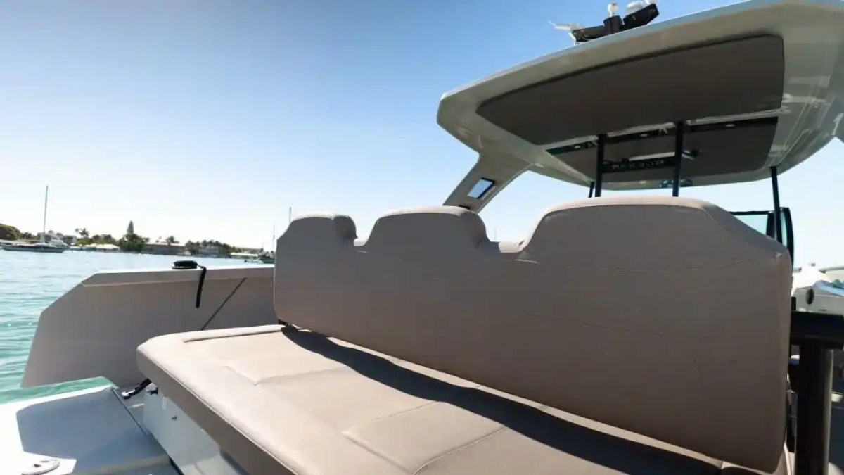 Boat interior with backless bench seat, canopy, and view of water and shoreline.