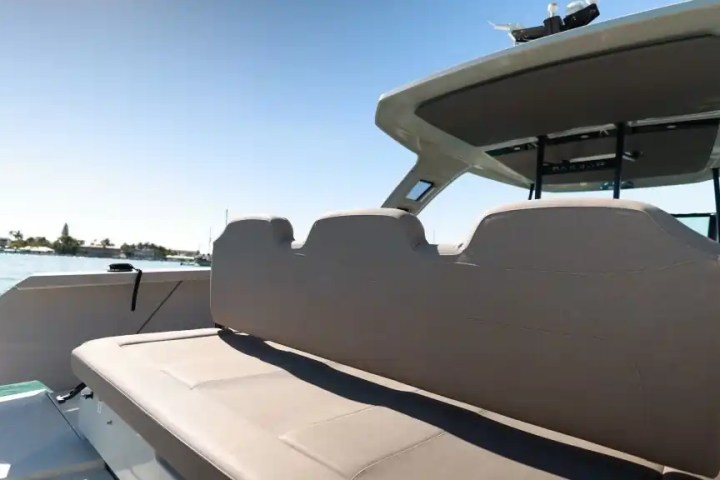 Boat interior with backless bench seat, canopy, and view of water and shoreline.