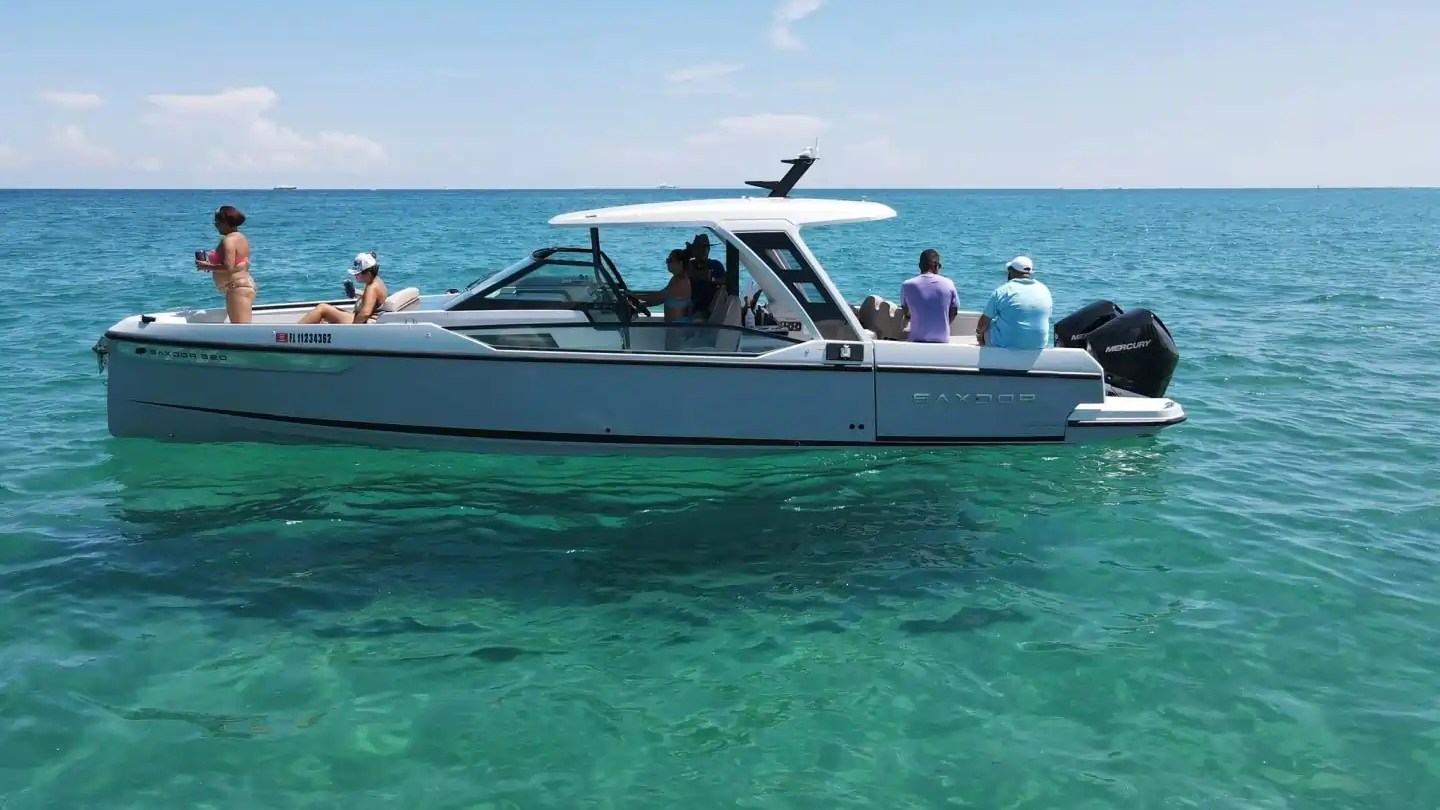 People on a motorboat in clear blue water under a sunny sky.