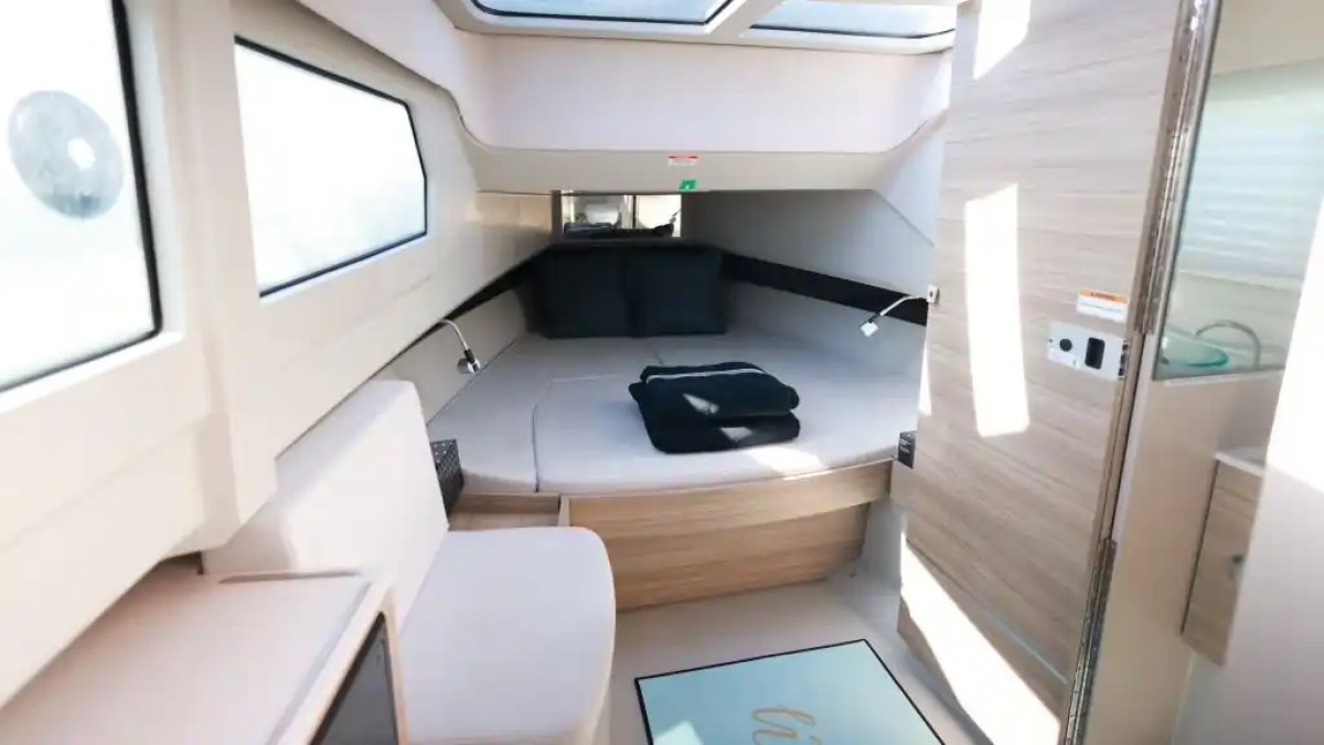 Interior of a modern boat cabin with a bed, skylight, and windows.