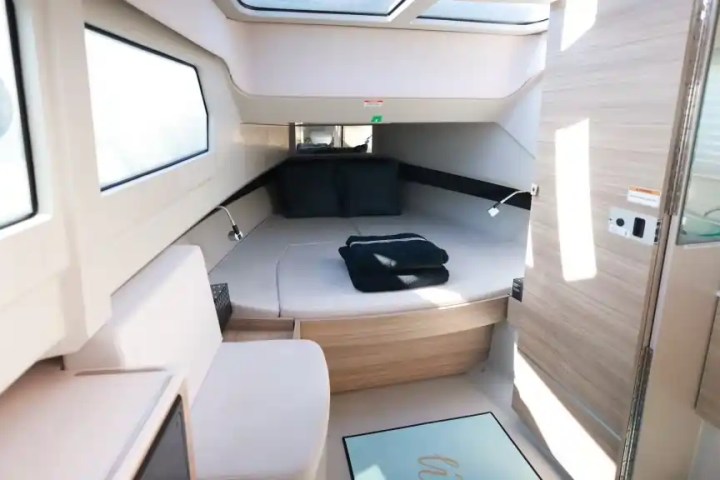 Interior of a modern boat cabin with a bed, skylight, and windows.