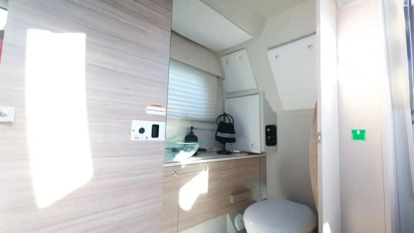 Compact RV bathroom with sink, mirror, cabinets, and toilet.