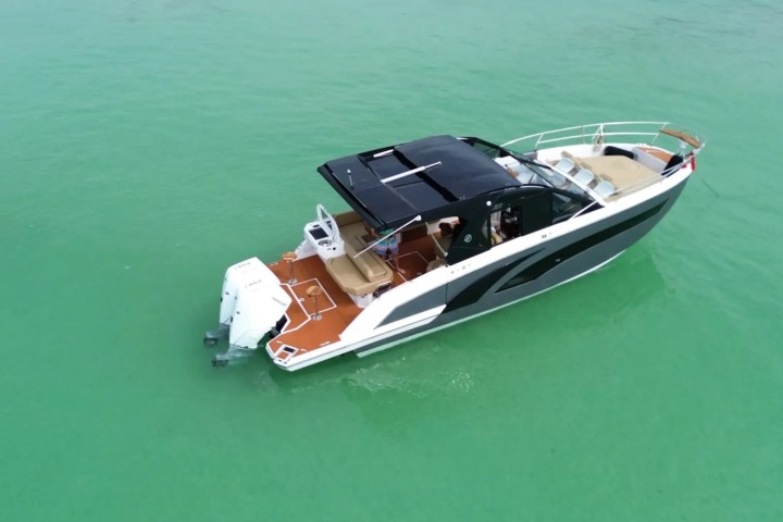 A modern motorboat with a black canopy on turquoise water.