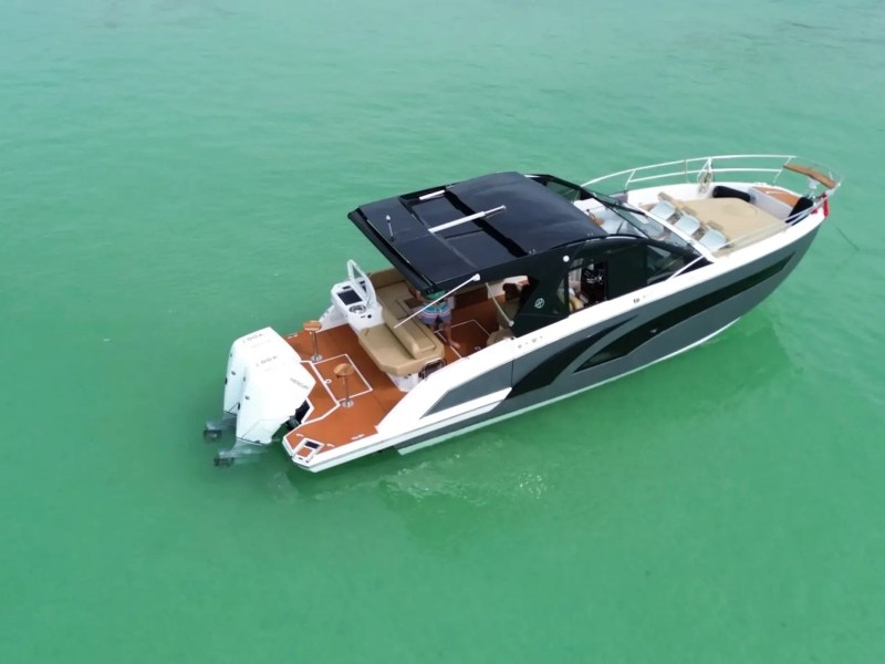 A modern motorboat with a black canopy on turquoise water.