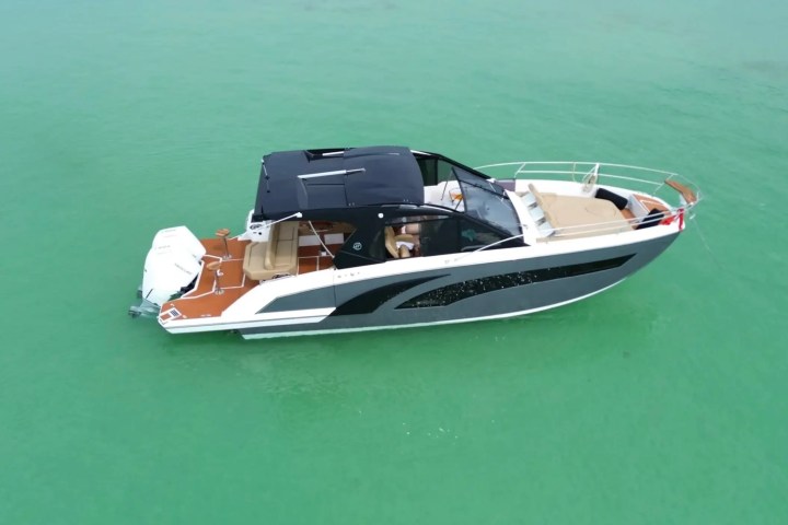 Motorboat with black canopy on turquoise water, aerial view.