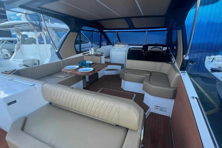 Interior cabin of a boat with beige seating, a wooden table, and nautical accessories.