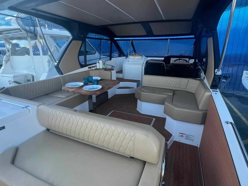 Interior cabin of a boat with beige seating, a wooden table, and nautical accessories.