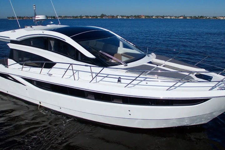 White yacht with sleek design on calm blue water under a clear sky.
