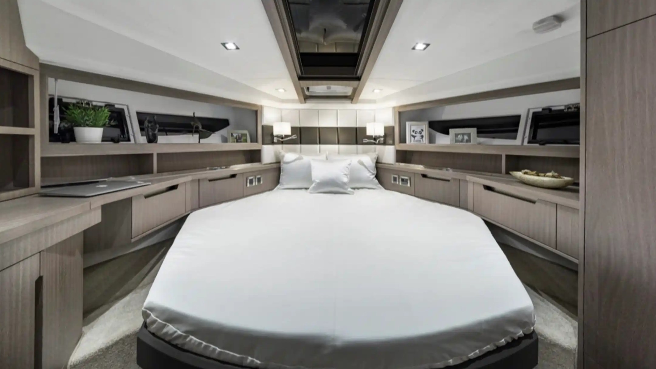 Modern bedroom with white bed, wooden cabinets, skylight, and decorative items.