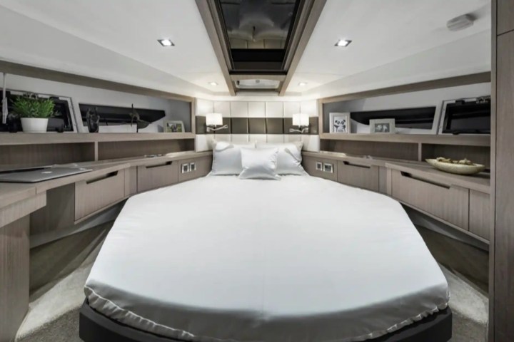 Modern bedroom with white bed, wooden cabinets, skylight, and decorative items.