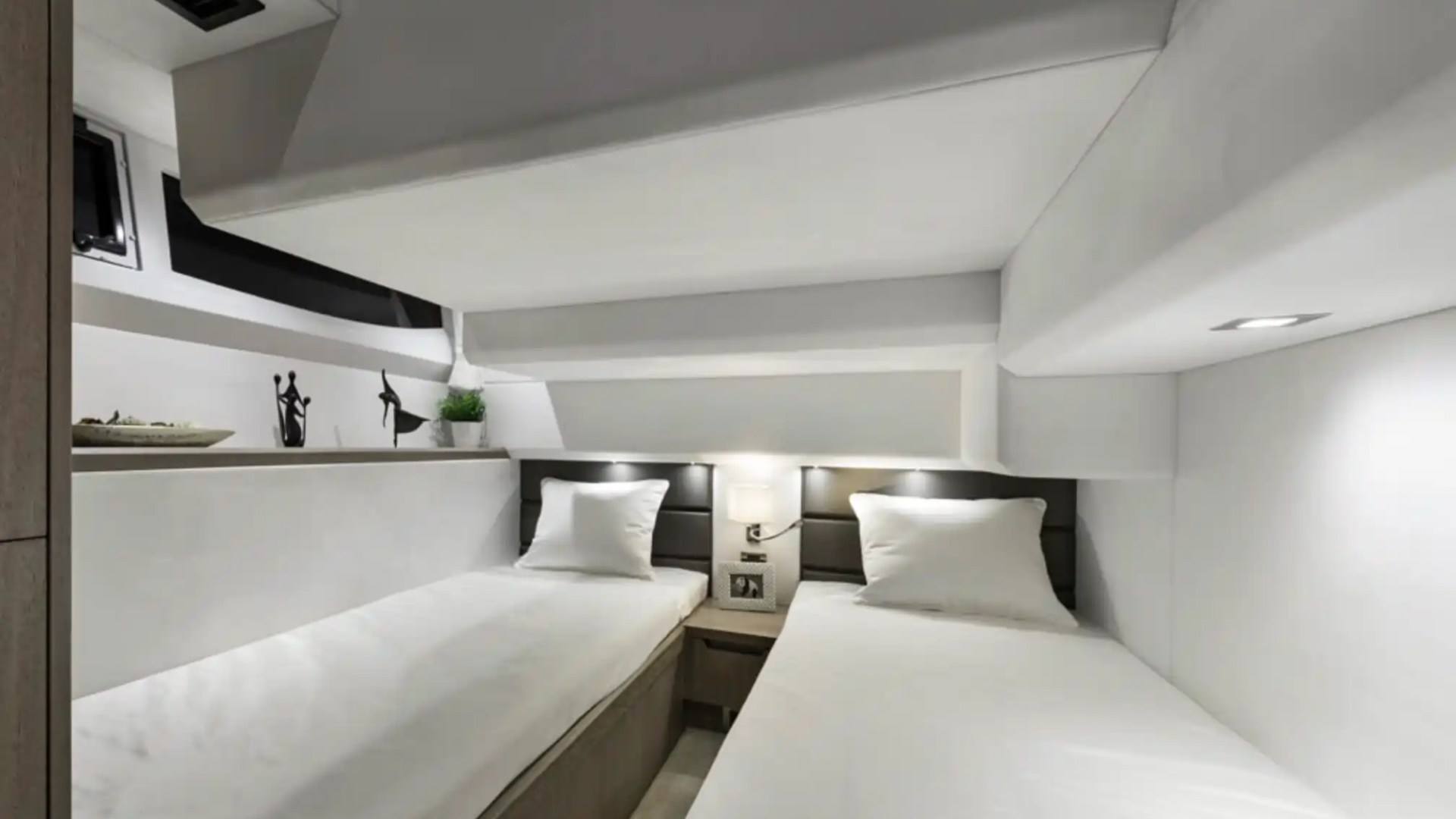 A minimalist white bedroom with two single beds and a small nightstand.