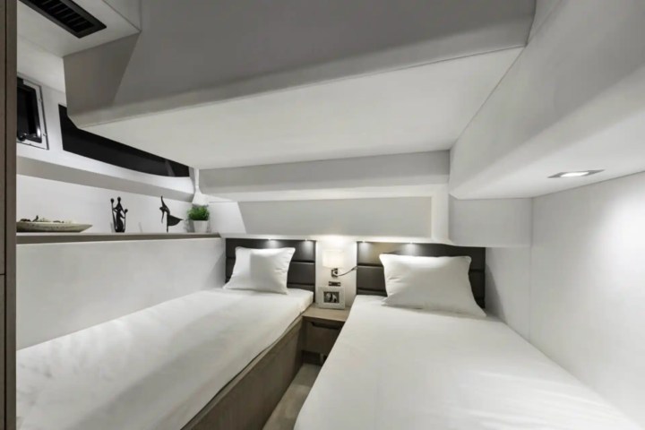 A minimalist white bedroom with two single beds and a small nightstand.