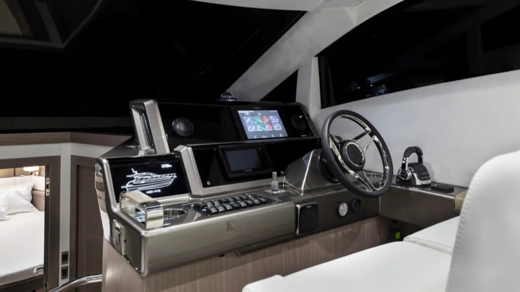Modern boat cockpit with steering wheel, screens, and controls.