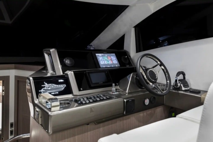 Modern boat cockpit with steering wheel, screens, and controls.