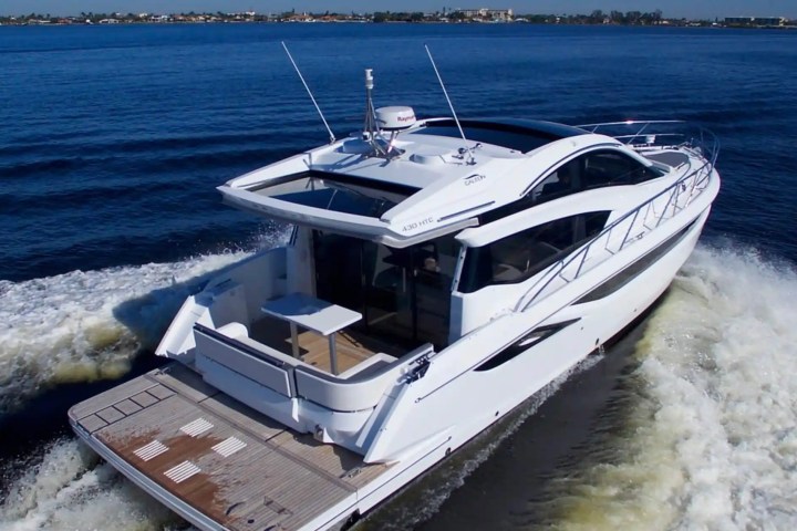 White luxury yacht cruising on blue water, leaving a wake behind.