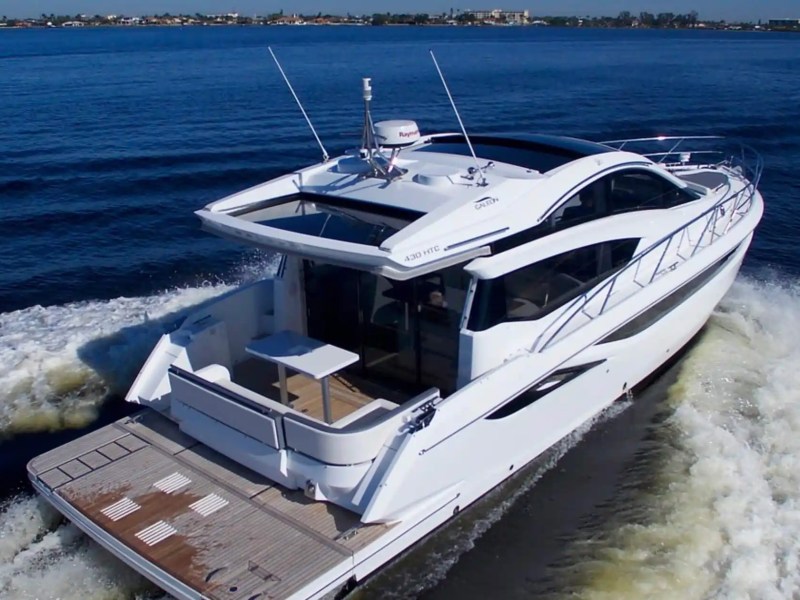 White luxury yacht cruising on blue water, leaving a wake behind.