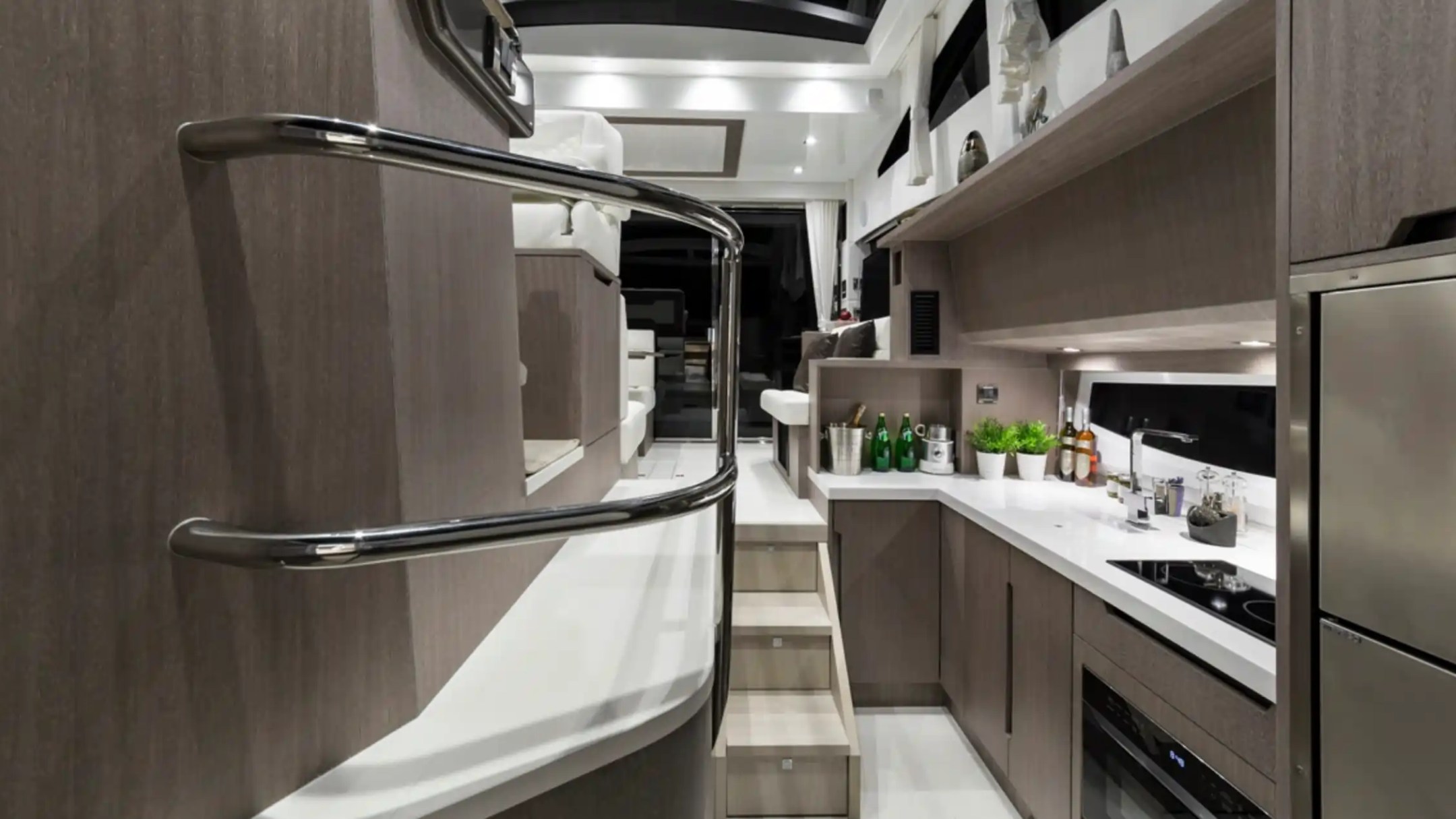 Modern yacht kitchen with sleek cabinets, stainless steel appliances, and a staircase.