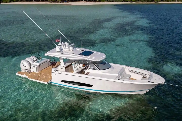 White motorboat anchored in turquoise waters with an island in the background.