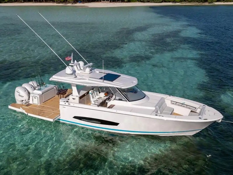 White motorboat anchored in turquoise waters with an island in the background.