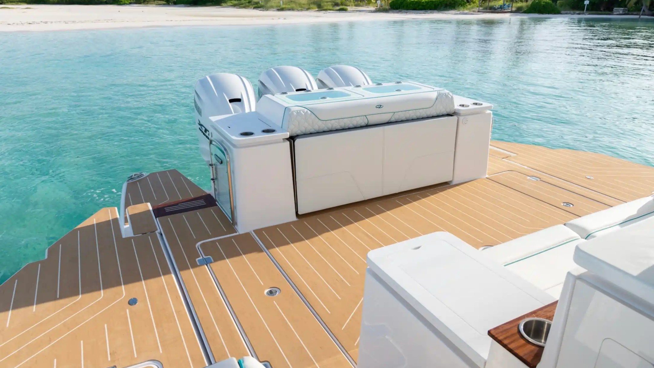 View of a boat's deck with outboard engines, overlooking a tropical shoreline.
