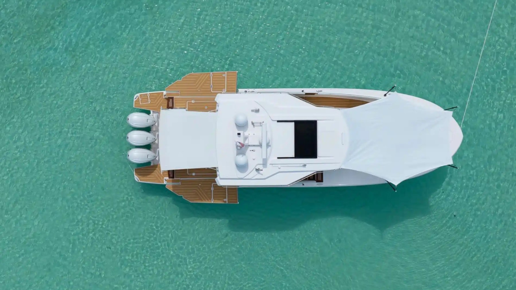 Aerial view of a white boat with a canopy on turquoise water.