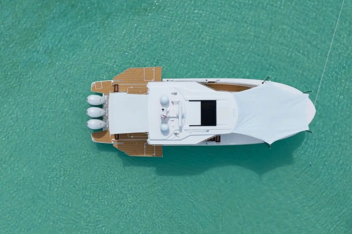 Aerial view of a white boat with a canopy on turquoise water.